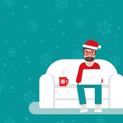 happy freelancer man with santa hat on sofa with laptop. creative hipster work at home.