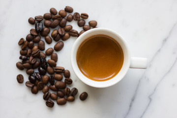 Small espresso cup with coffee beans isolated on marble background