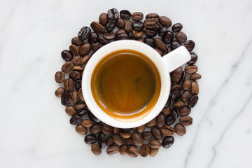 Small espresso cup with coffee beans isolated on marble background