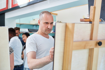 Fototapeta premium Artist paints concentrated on canvas in art class