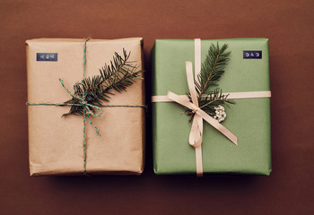 Close-up of two Christmas gift boxes decorated fir branches isolated on brown background