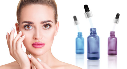 Cosmetics oil in bottle near beautiful face of young woman.