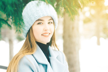 Happy young woman with beautiful blue eyes with natural make-up in a sweet smile in a knitted hat...