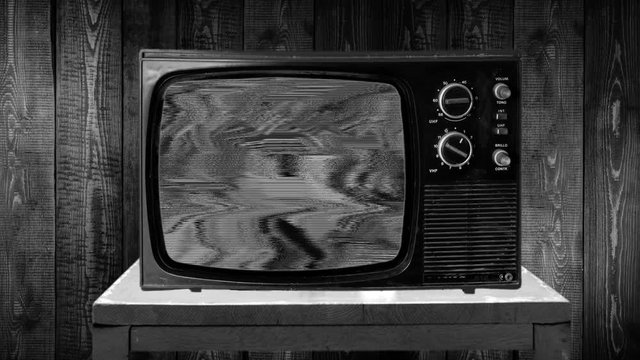 Zoom in then fixed view on a old tv set with static black and white sizzles