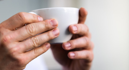 the white cup and the hands of the man, isolated from background and focused  