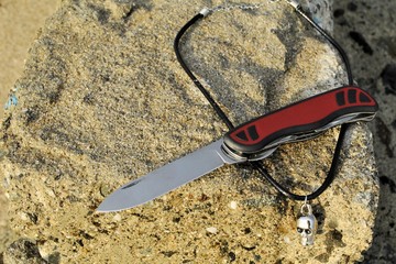 Obraz premium Folding knife stainless blade black red handle travel vacation beach background