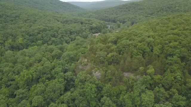aerial drone footage over trees and creek in ozark forest