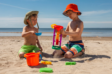 Two boys sitting on the sea beach playing sand with beach toys. Happy children kid enjoy and fun outdoor lifestyle on beach holiday. Together on summer vacation.
Beach Toys in the Sand. - obrazy, fototapety, plakaty