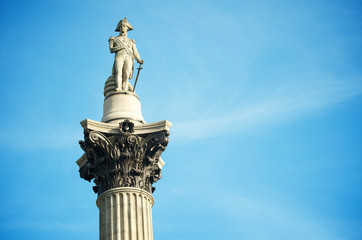 Sunny view of Admiral Nelson standing atop his column (constructed 1843) against blue sky in Trafalgar Square, London, UK 