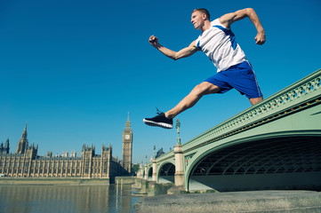 Fototapeta na wymiar Giant British athlete jumping over Big Ben and the Houses of Parliament in Westminster, London, UK