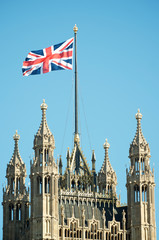 Fototapeta na wymiar Close up view of Union Jack Flag flying atop the Gothic tower architecture of the Houses of Parliament in Westminster, London, UK