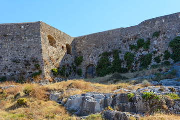 bottom view of the mountain with part of the stone wall with wooden doors of the fortress of Fortezza. Summer, Greece, Rethymno.