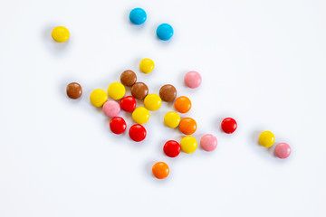 Scattered multi-colored small round candies. Chocolate dragees in multi-colored glaze on a white background
