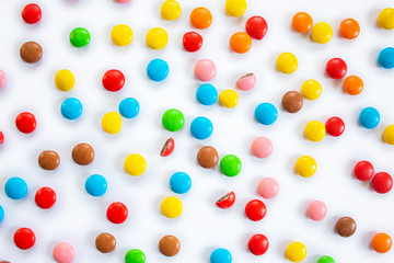 Scattered multi-colored small round candies. Chocolate dragees in multi-colored glaze on a white background