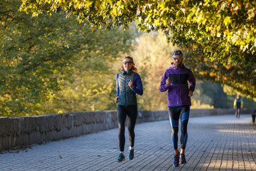 Obraz premium Young couple running in autumn park in the morning