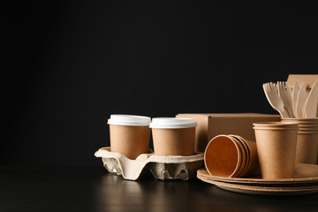 Eco - friendly dishware and carton box on black background, space for text