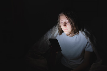 Woman in bed uses phone late at night. Insomnia and browsing social media at late hours instead of...