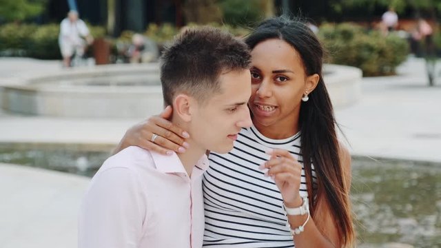 Beautiful black woman showing keep silence gesture while whispering something in boyfriend's ear. She telling him some special things.