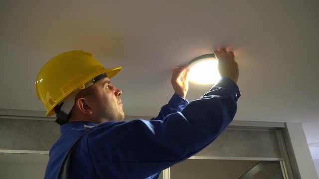Electrician man remove led panel light from ceiling and inspect wire connections