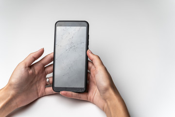 Women's hands with a mobile phone with a broken screen.