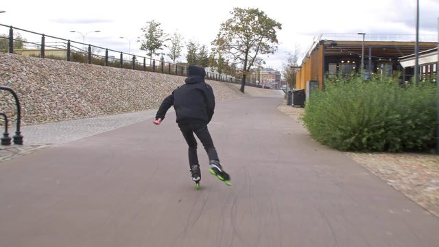 Inline Skater in black enjoying recreation fitness skating on promenade