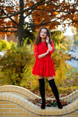 girl with curls in a red dress on an autumn city alley