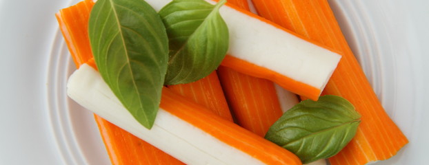 sechs frische Surimi mit Basilikum auf einem Teller