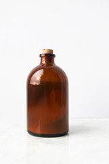 Glass brown bottle with organic ubtan powder on white background, vertical. Hand made organic skin care product, body cleanser and scrub