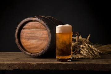 Oktoberfest beer barrel and beer glasses with wheat and hops on wooden table