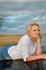 Fototapeta na wymiar Young blonde hunted her black car 