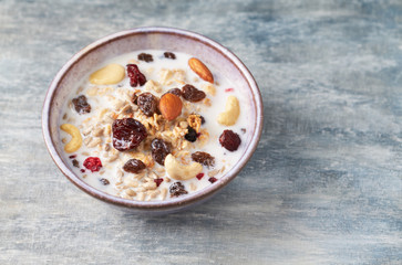 Bowl of granola with milk, nuts, raisins and cranberries. Concept for a tasty and healthy meal. Rustic wooden background. Close up.