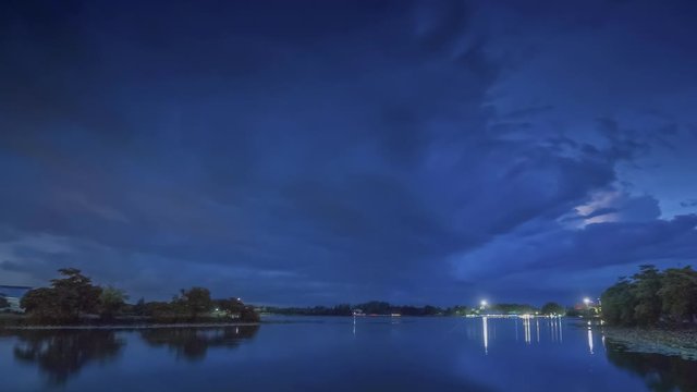 Time lapse at night of dark clouds moving above the lake with rain storm in the sky background, Krajub reservoir, Nonk Kop in Ban Pong District, Ratchaburi, Thailand.