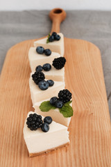 slices of classic cheesecake decorated with berries on a wooden board