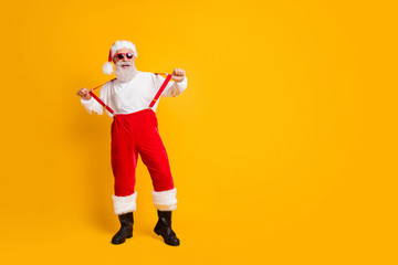 Fototapeta na wymiar Full size photo of funny funky cool santa claus hipster enjoy fun christmas x-mas party celebration pull red suspenders wear black boots isolated over bright color background