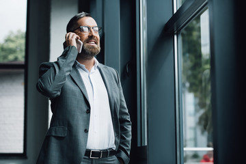handsome businessman in formal wear and glasses talking on smartphone