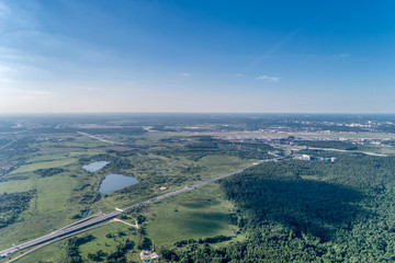 Large green forest. A multi-lane highway runs through the forest. Aerial view, summer sunny day.