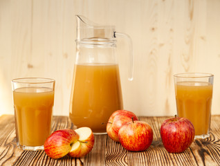 Ripe apples and freshly squeezed juice in glasses on a wooden table