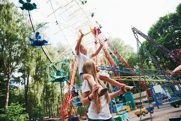 Walking with daughter on the shoulders. Cheerful little girl her mother have a good time in the...