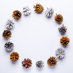 Painted pine cones frame on light grey background, Christmas golden and silver decorations flat lay, copy space, top view