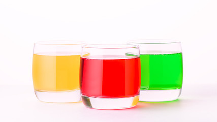 Glasses of various colors and tastes soda drink on white background. Red, yellow, green soda or sparkling water close up on white table, copy space