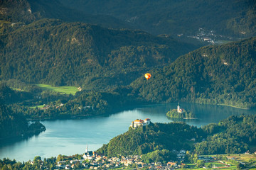Hot air ballon over lake bled and bled island from the side of mountain zoomed up. Adventure in...