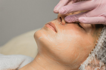 concept beautician. The hands of a cosmetologist put cream on the face of a woman. Beautician applies a cream to the face of the girl.