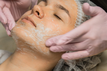 concept beautician. The hands of a cosmetologist put cream on the face of a woman. Beautician...