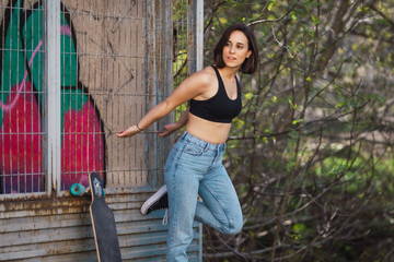 Young woman skater grabs ancient metal fence freedom concept