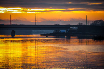 Traffic, cars and bridge over the river at beautiful sunrise