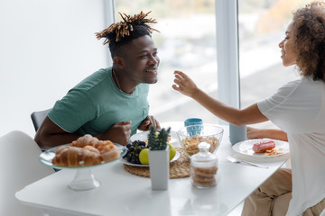 Cheerful young lady feeding her boyfriend in cafe