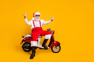 Fototapeta na wymiar Don't need your advises. Full body photo of crazy white hair santa sitting bike showing impolite gestures wear sun specs pants cap shirt boots isolated yellow color background