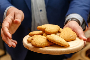 Men's hands with heart-shaped cookies on a wooden plate
