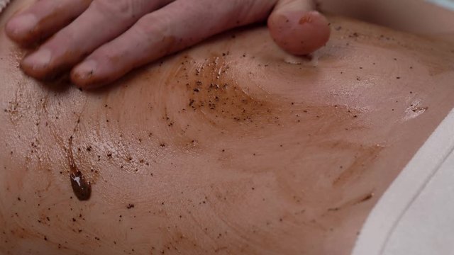 Close-up of the therapist massaging beautiful female clients body during chocolate wrapping procedure. Spa and aromatherapy concept