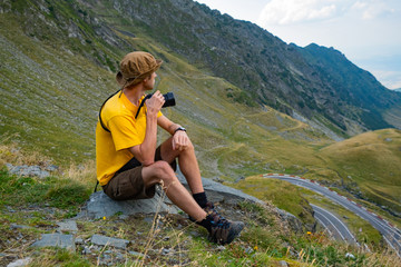 Young male traveler with photocamera in the mountains